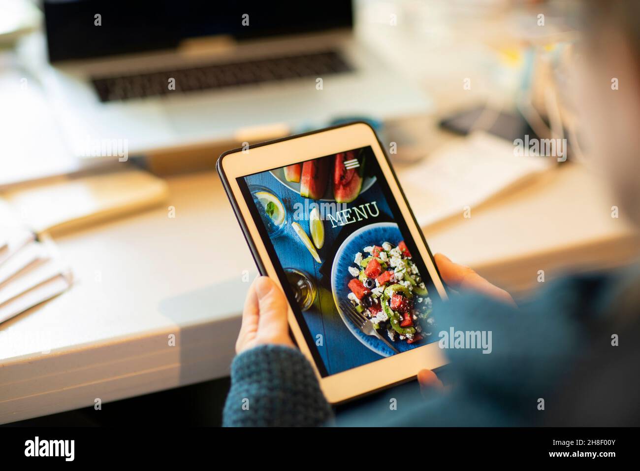 Frau, die auf dem digitalen Tablet das Menü zum Mitnehmen ansieht Stockfoto