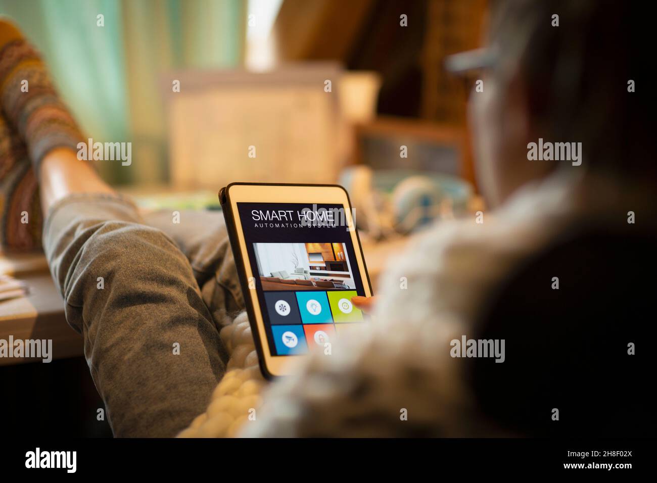 Frau, die Smart Home Automation auf dem digitalen Tablet-Bildschirm betrachtet Stockfoto
