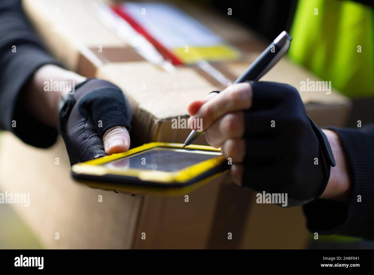 Nahaufnahme Kurier mit Smartphone und Stift Lieferung Paket Stockfoto