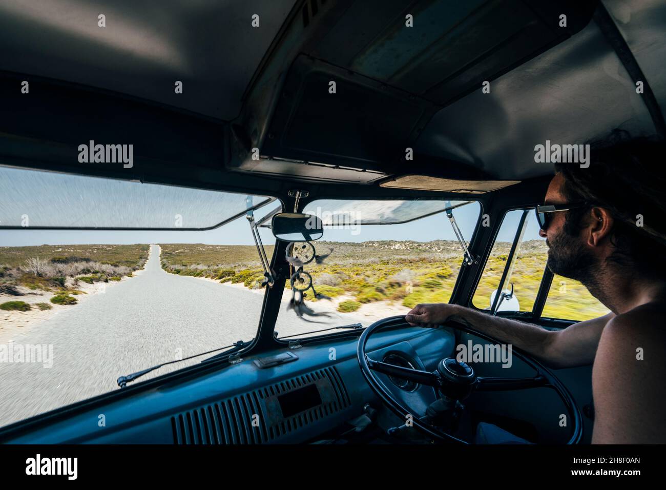 Mann, der auf einer abgelegenen Straße im australischen Busch einen Van fährt Stockfoto