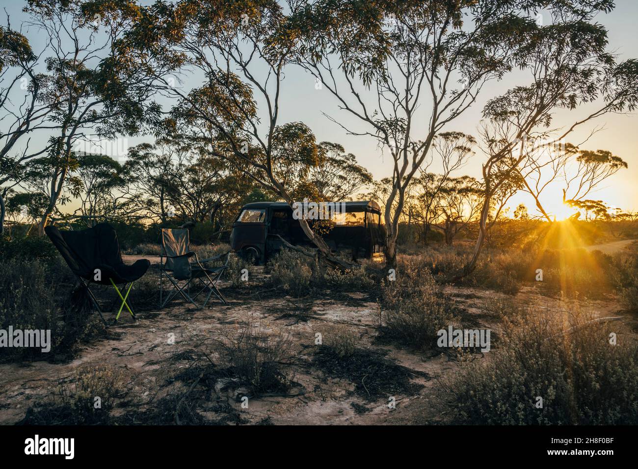Campingstühle und geparkter Van im australischen Busch bei Sonnenuntergang Stockfoto