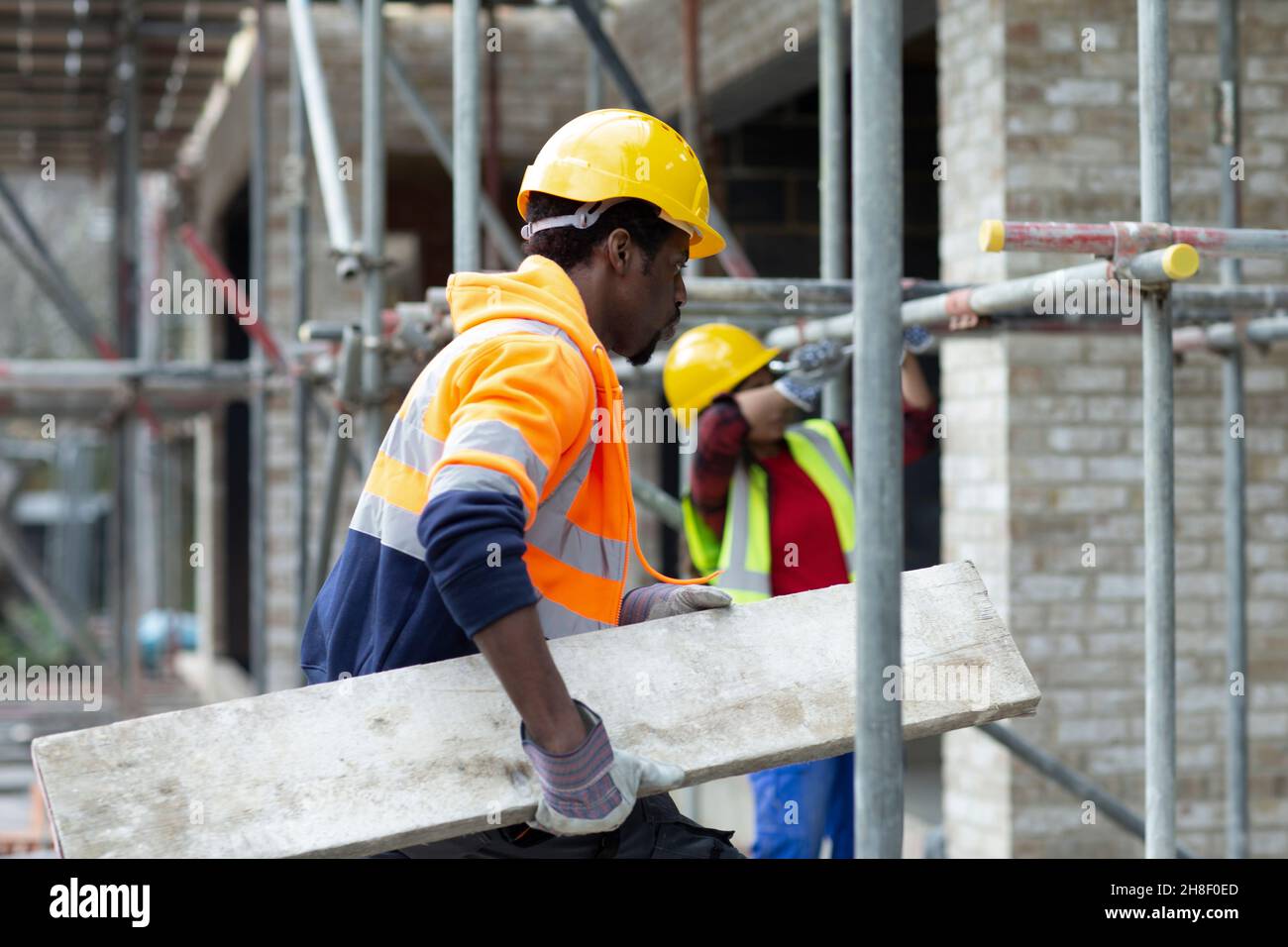 Bauarbeiter, der Holz auf der Baustelle transportiert Stockfoto