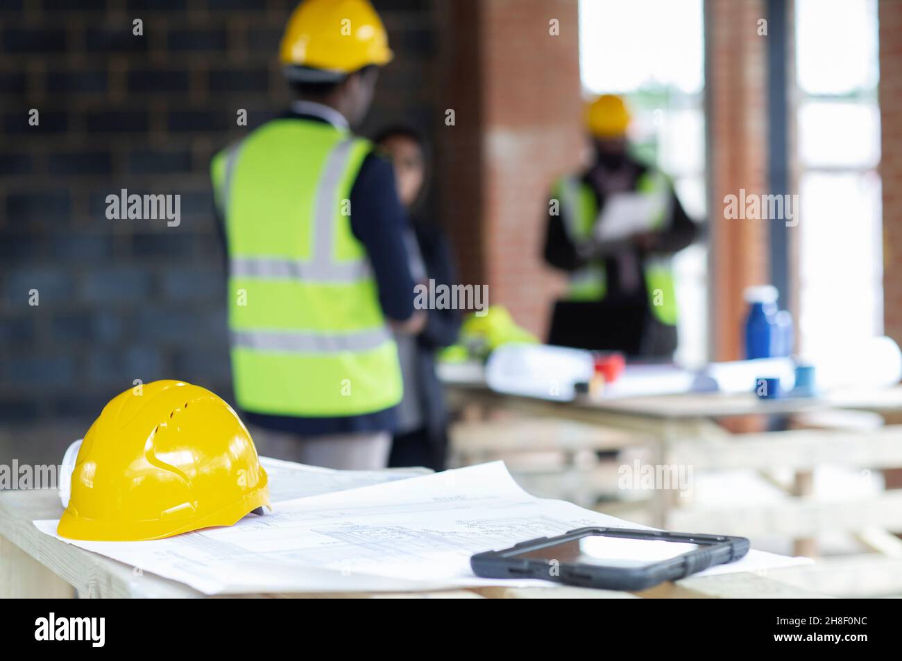 Hardhut und digitales Tablet auf Bauplänen auf der Baustelle Stockfoto
