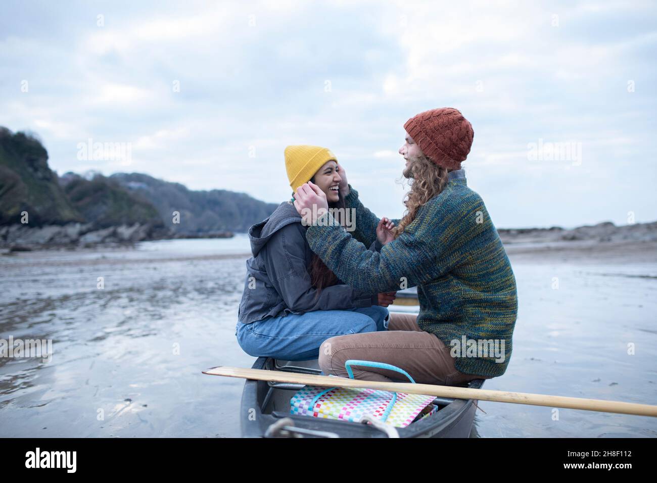 Glückliches junges Paar im Kanu auf Meeresbrandung Stockfoto