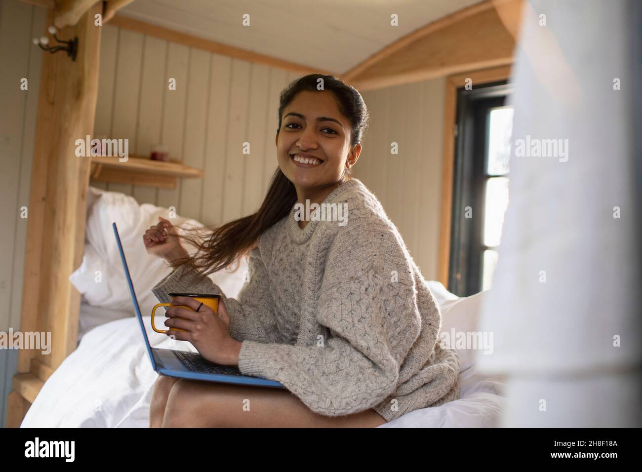 Portrait glückliche junge Frau mit Laptop im Bett Stockfoto