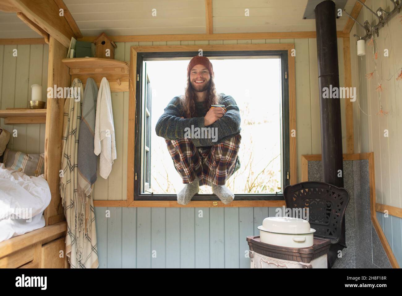 Portrait glücklicher junger Mann im Schlafanzug in winzigen Kabinenfenster Stockfoto