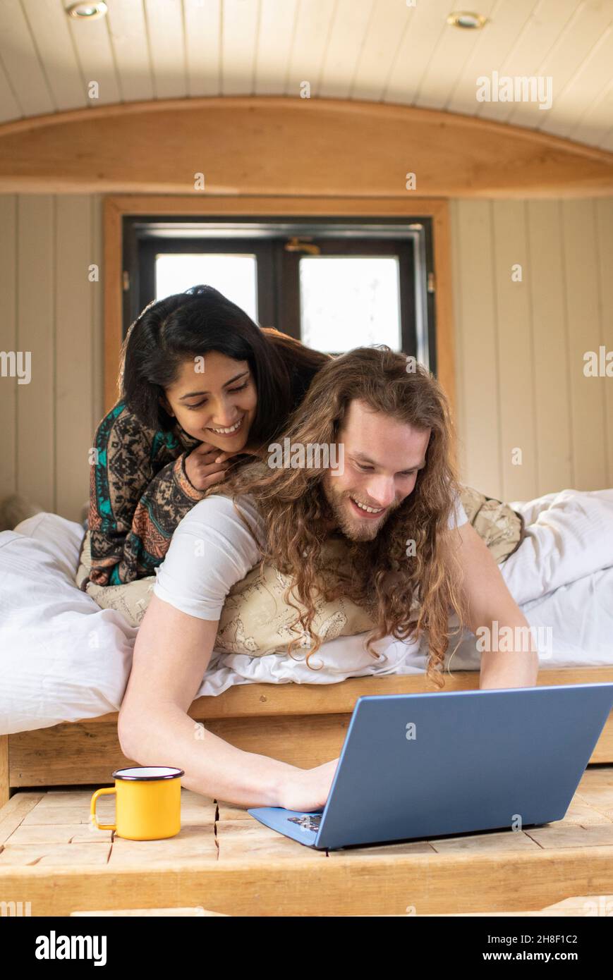 Glückliches junges Paar, das in einer winzigen Kabine einen Laptop benutzt Stockfoto