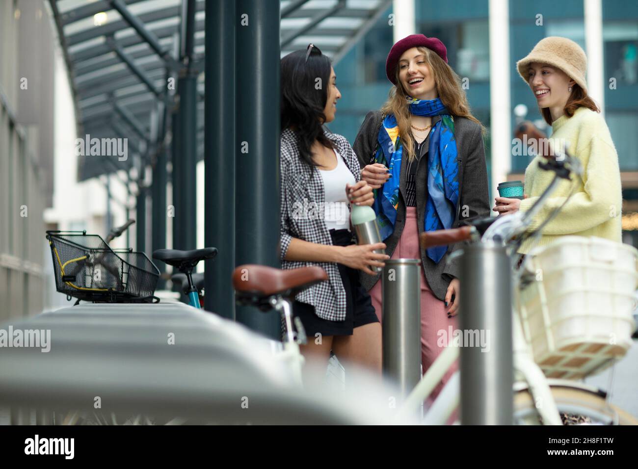 Glückliche junge Freundinnen, die auf dem Bürgersteig reden Stockfoto