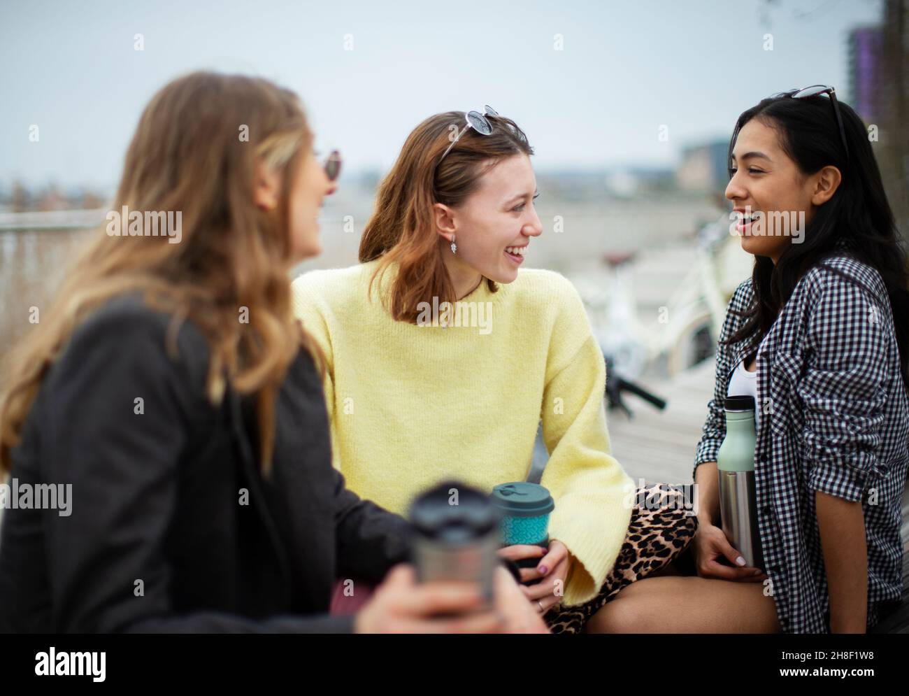 Glückliche junge Freundinnen reden und trinken Kaffee Stockfoto