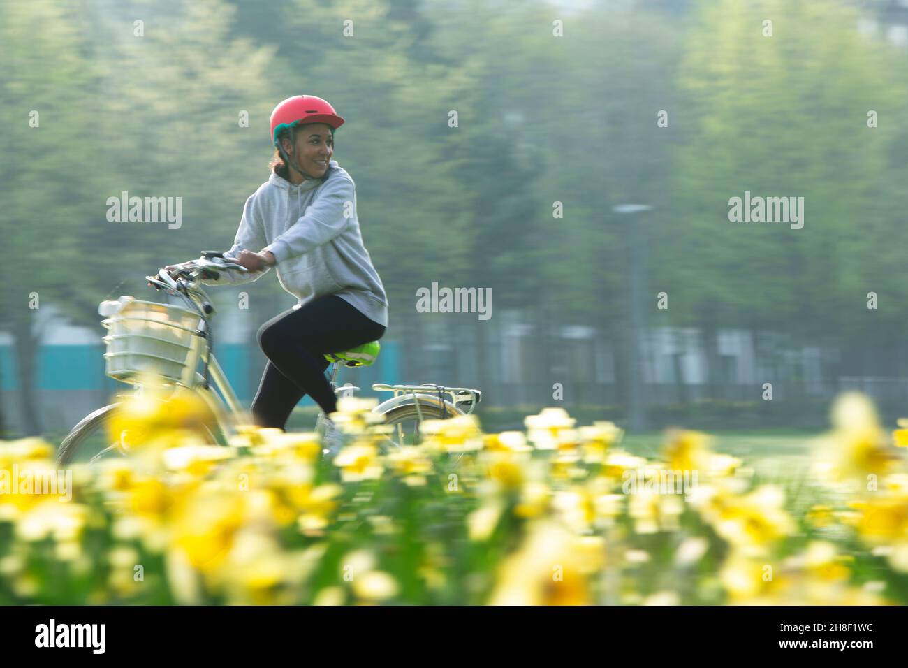 Glückliche junge Frau, die im sonnigen Frühlingspark Fahrrad fährt Stockfoto