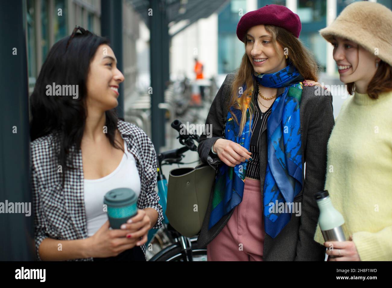 Glückliche junge Freundinnen, die auf dem Bürgersteig reden Stockfoto