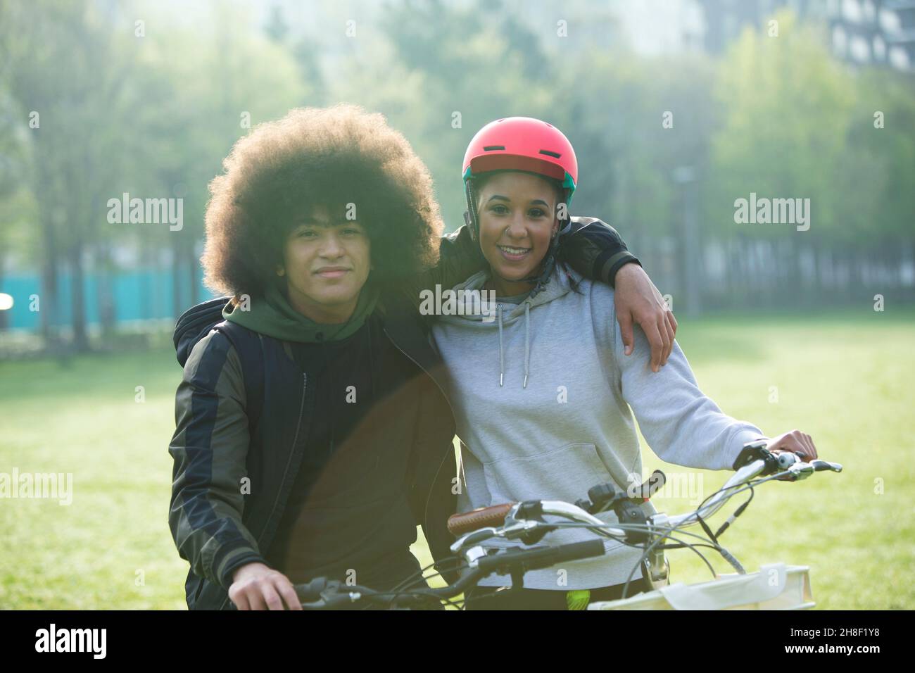 Portrait glücklich teen paar Umarmung auf Fahrrädern im Park Stockfoto