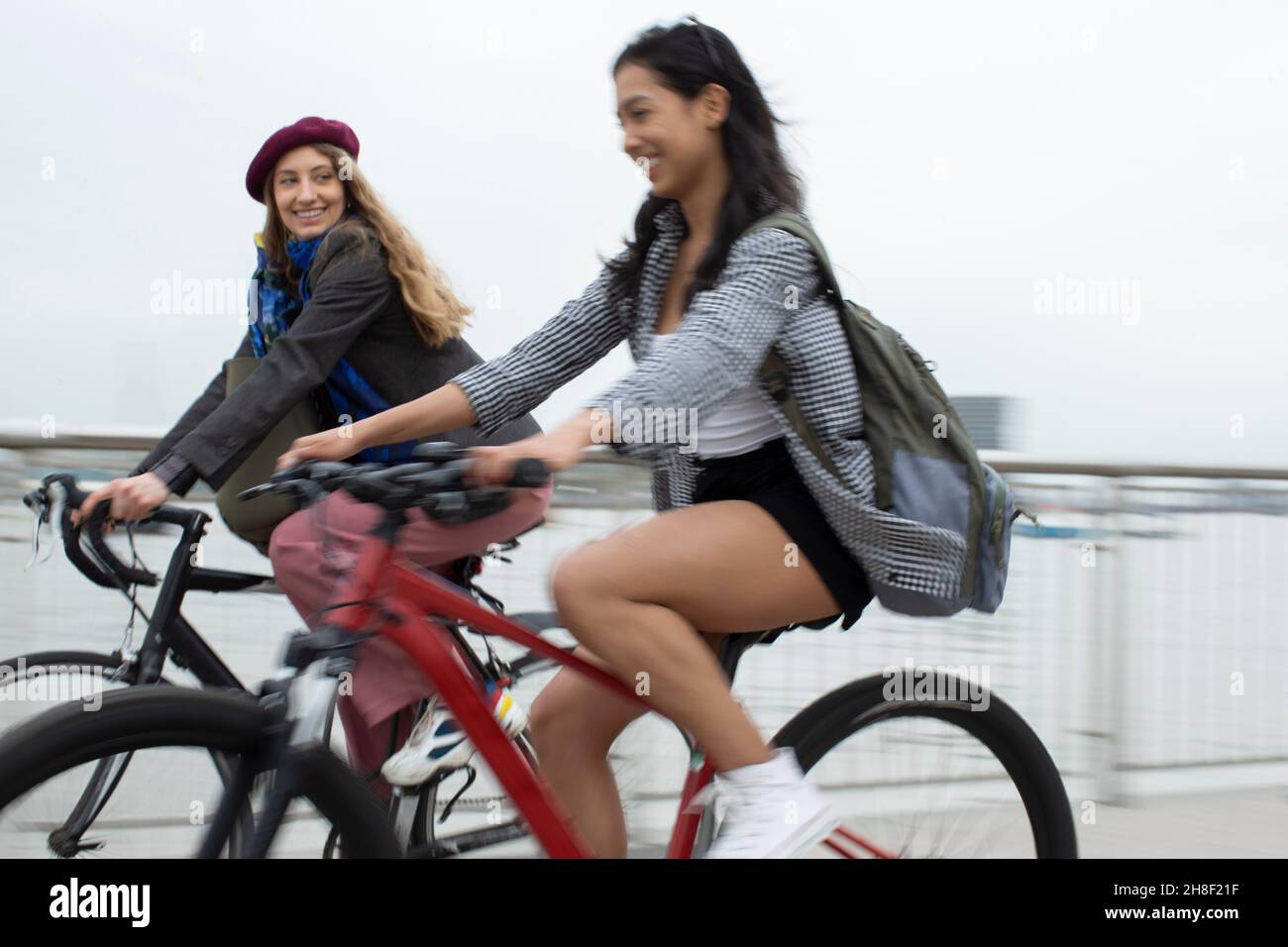 Glückliche junge Freundinnen, die auf der Brücke Fahrrad fahren Stockfoto