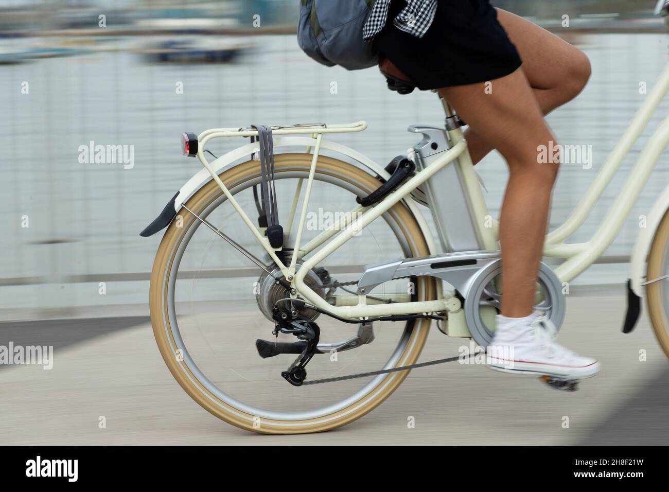 Junge Frau, die auf dem Bürgersteig Fahrrad fährt Stockfoto