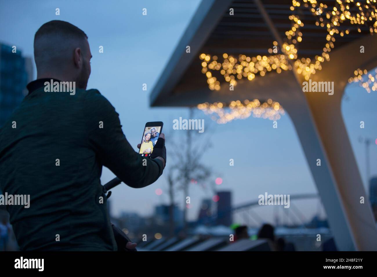 Mann Video chattet mit Familie auf Smartphone unter Brücke in der Nacht Stockfoto