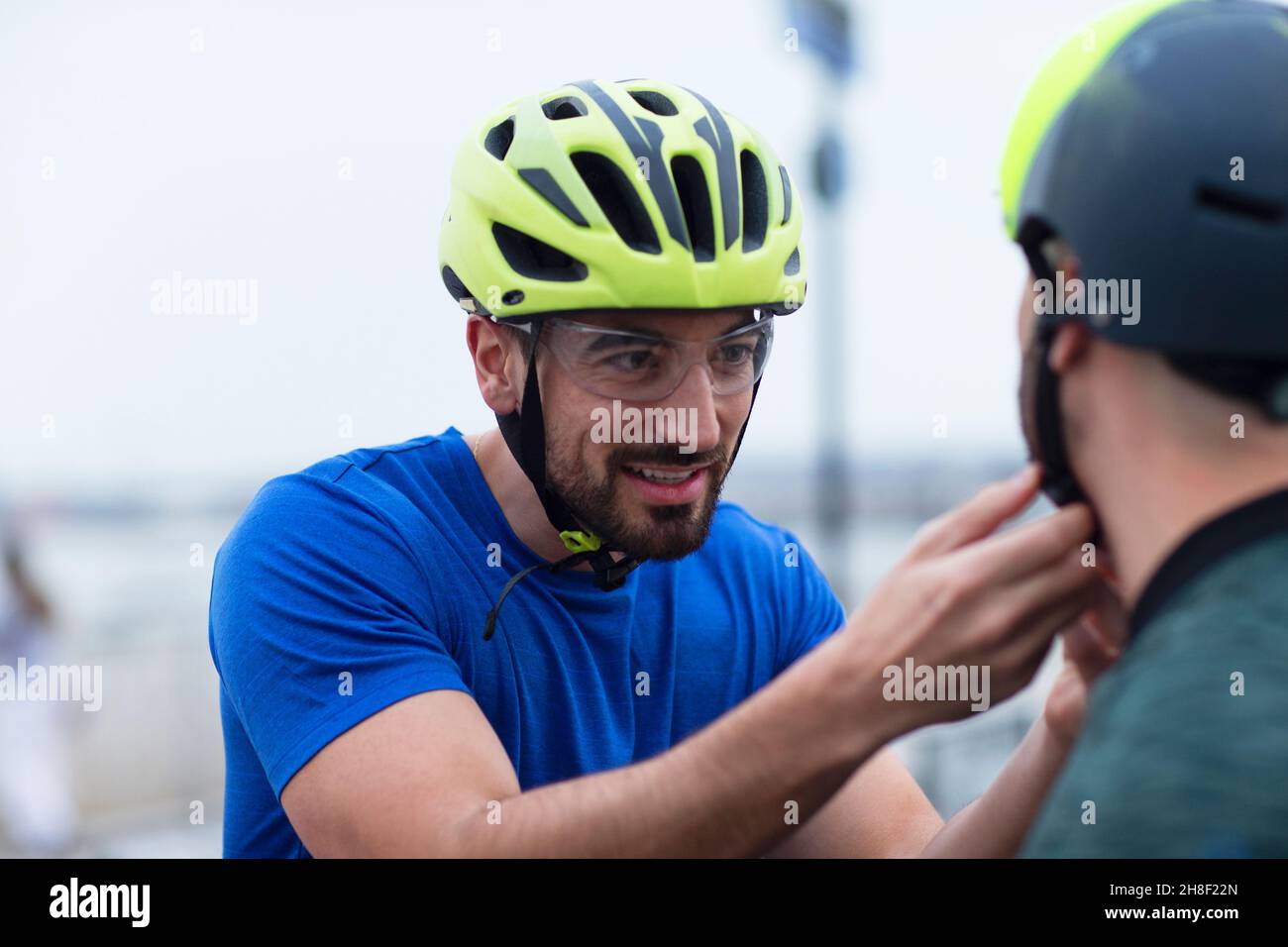 Mann hilft Freund mit Fahrradhelm Stockfoto