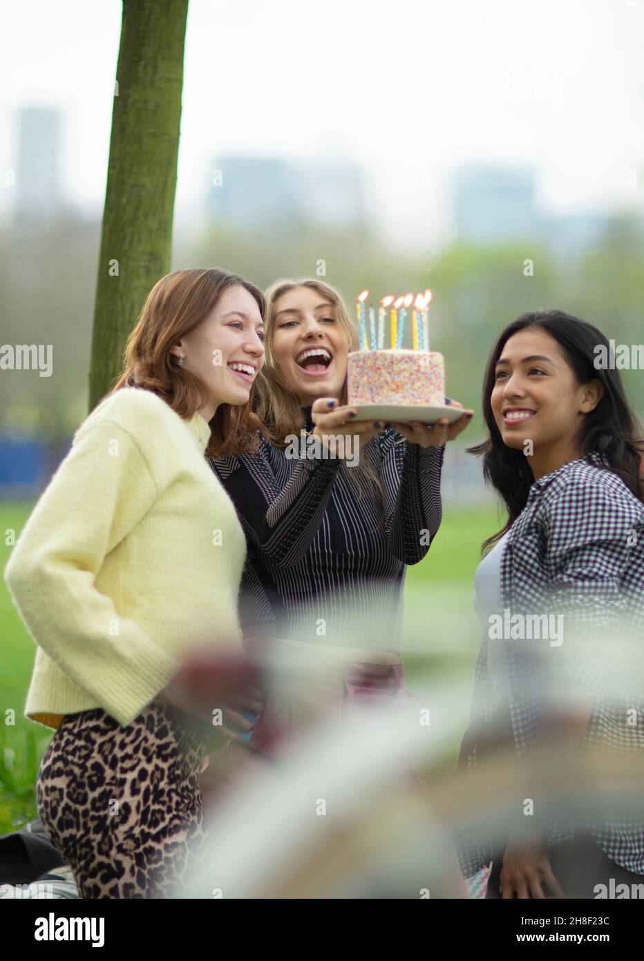 Glückliche junge Freundinnen feiern Geburtstag mit Kuchen Stockfoto