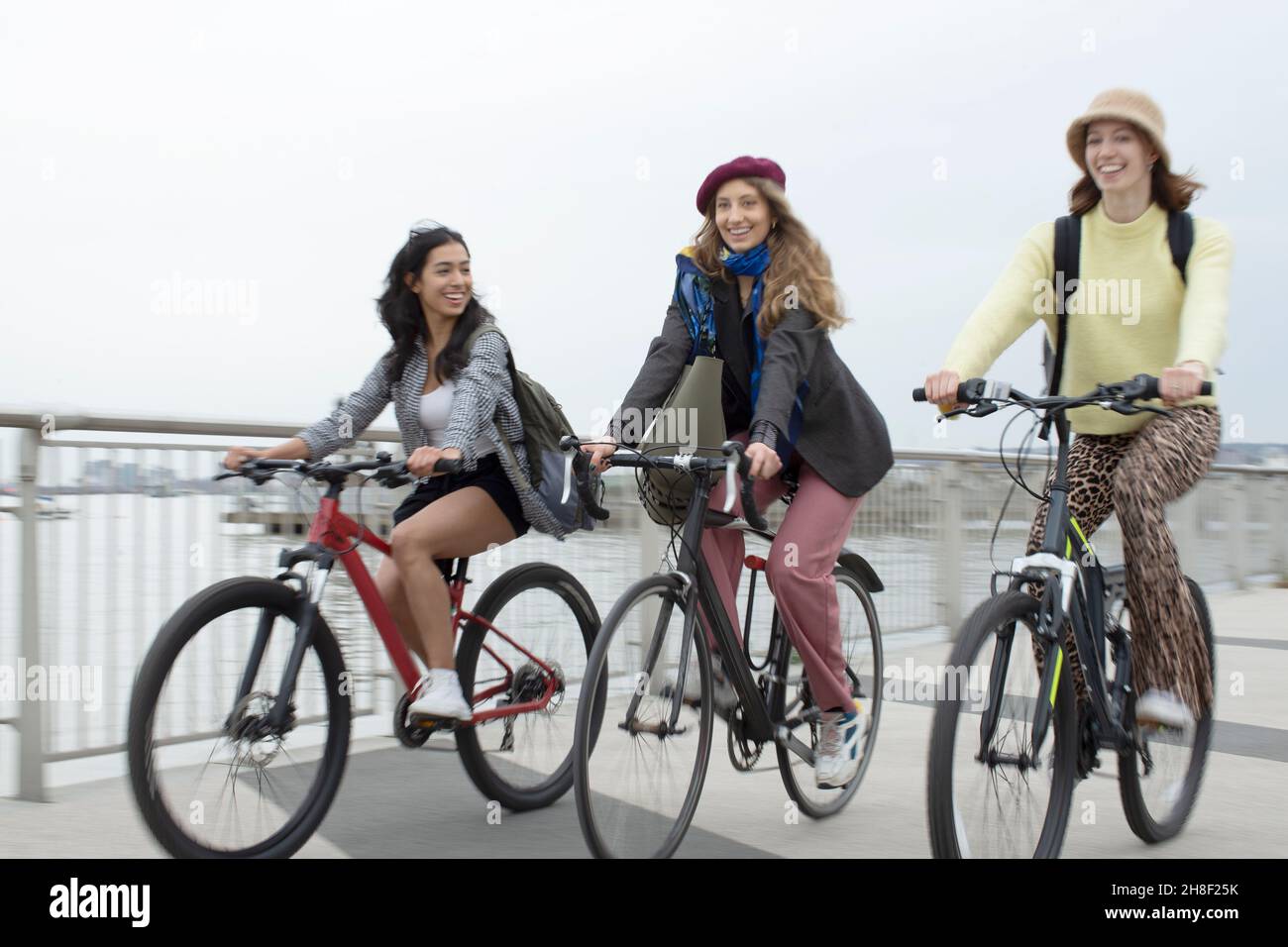 Glücklich. Junge Freundinnen reiten Fahrräder auf städtischen Fußgängerbrücke Stockfoto
