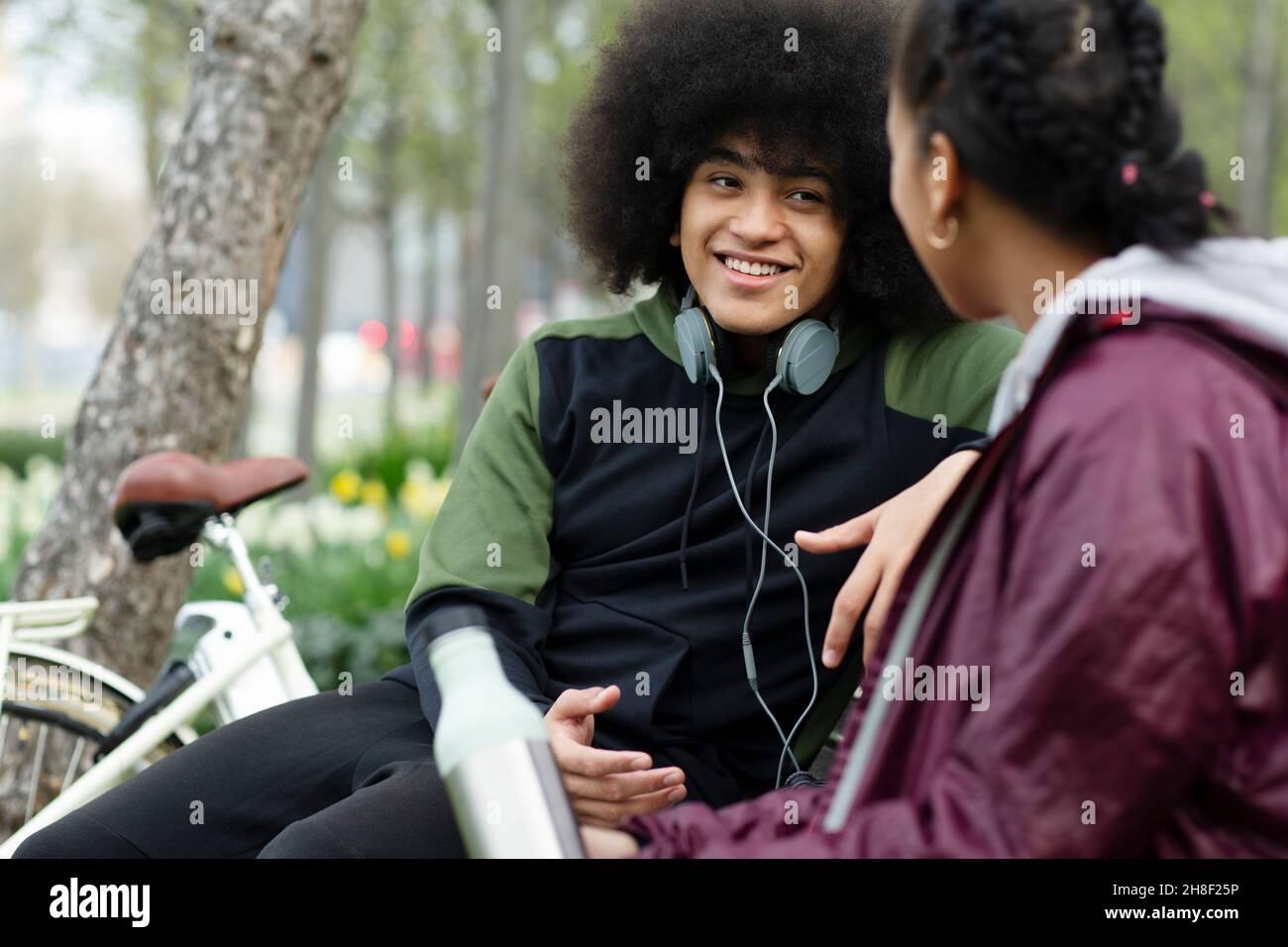 Junger Mann mit Afro im Park im Gespräch mit einem Freund Stockfoto