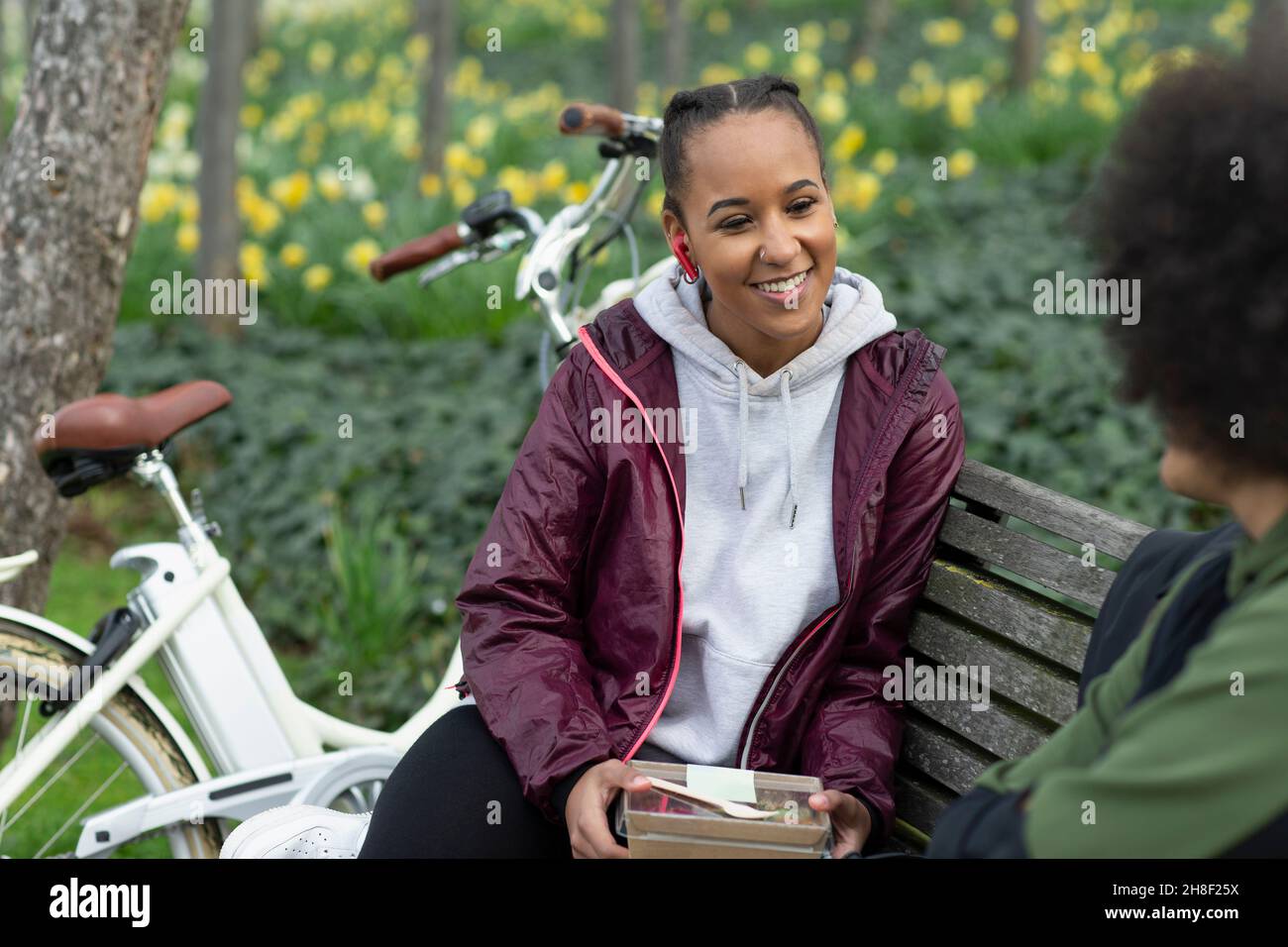 Glückliche junge Frau, die mit einem Freund auf der Parkbank zu Mittag gegessen hat Stockfoto
