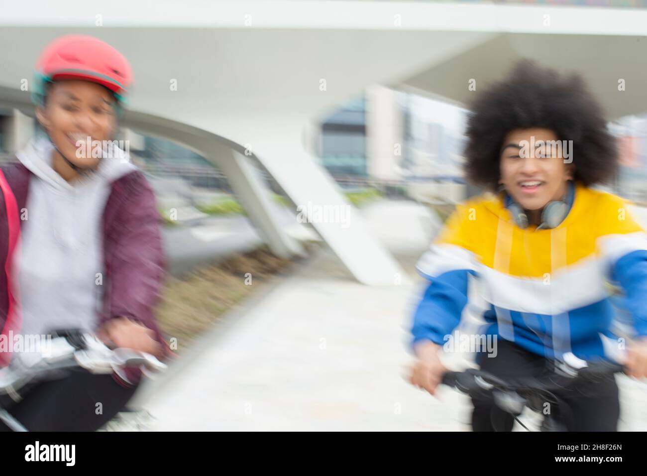 Glückliche Teenager-Freunde, die in der Stadt Fahrräder reiten Stockfoto