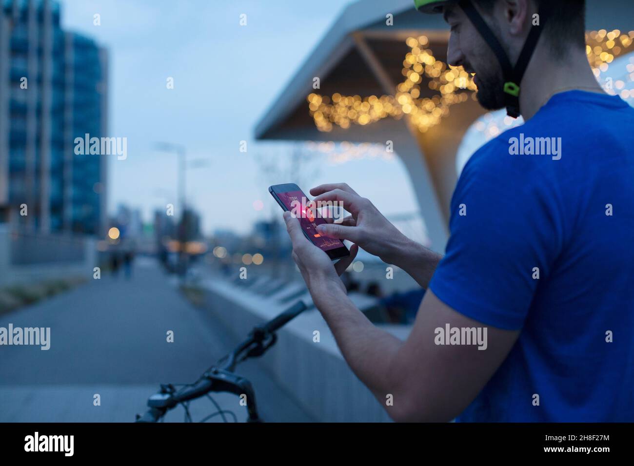 Mann auf dem Fahrrad, der die Herzfrequenz in der Smartphone-App in der Stadt ansieht Stockfoto