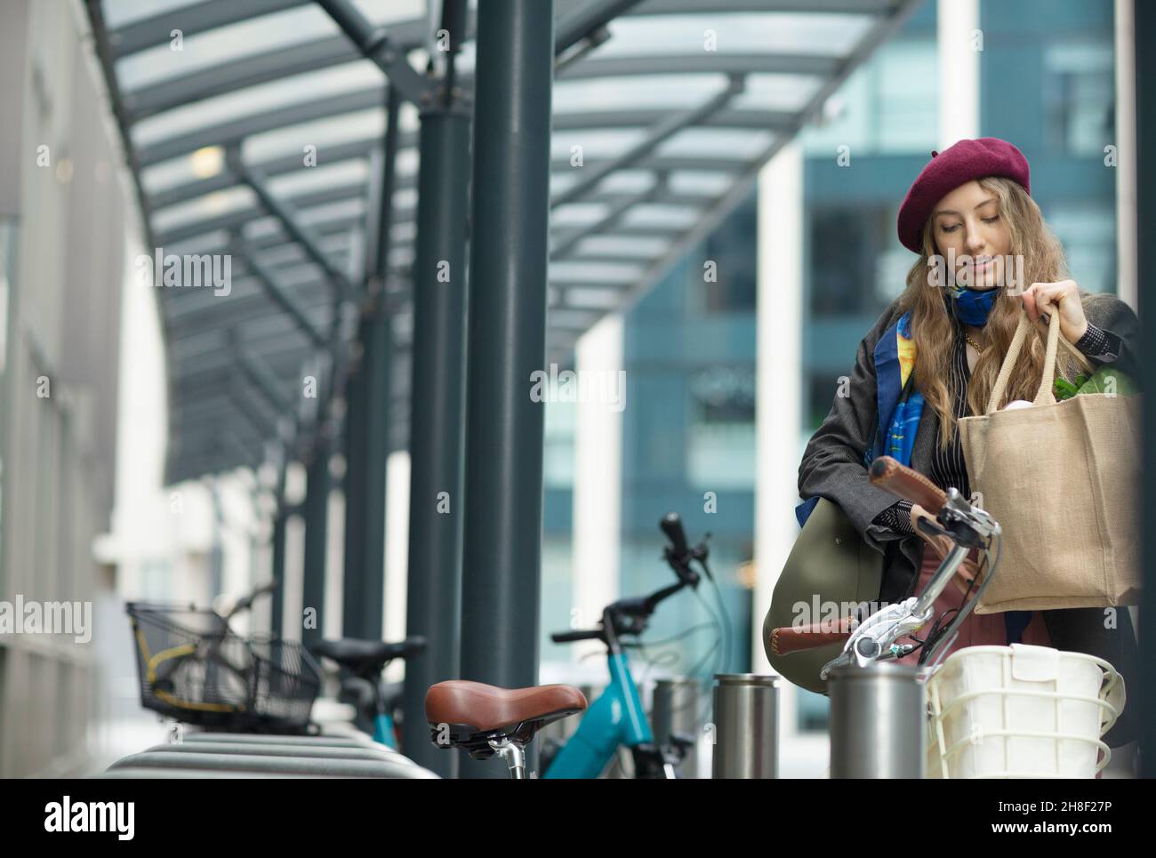 Junge Frau, die in der Stadt Lebensmittel in einen Fahrradwagen legt Stockfoto