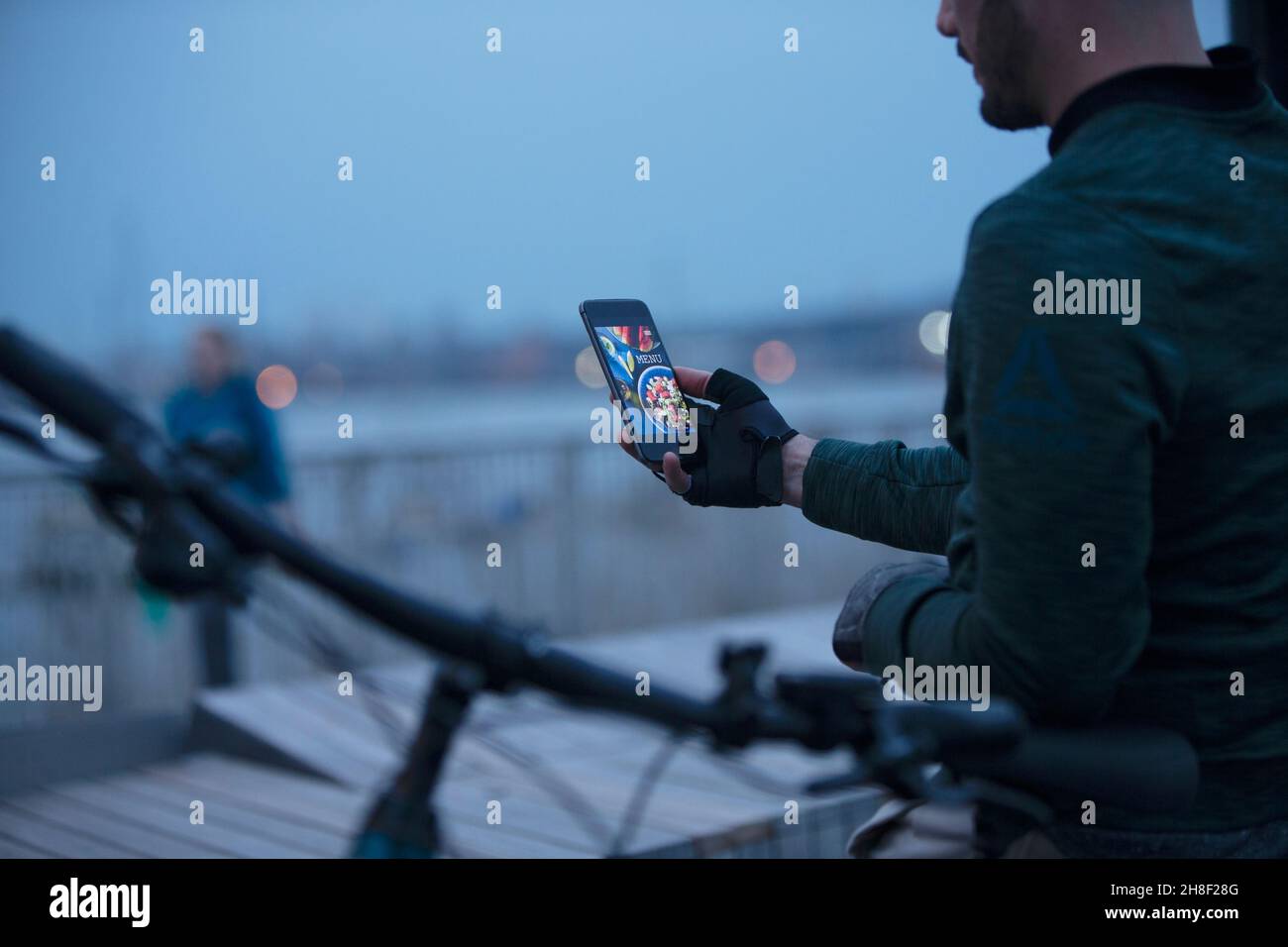 Mann, der abends mit dem Smartphone Essen zum Mitnehmen bestellte Stockfoto