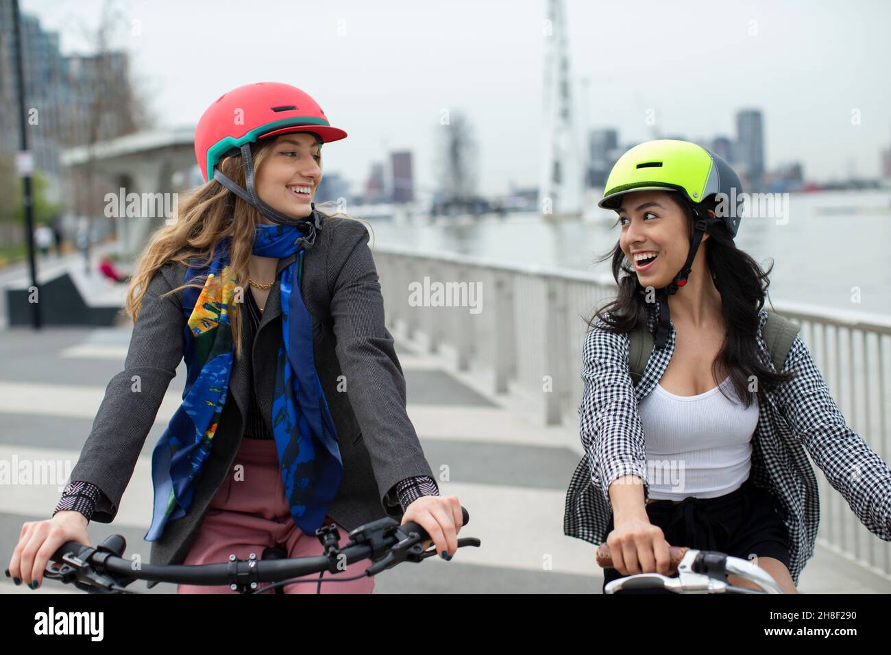 Glückliche junge Frauen Freunde in Helmen Fahrrad fahren in der Stadt Stockfoto