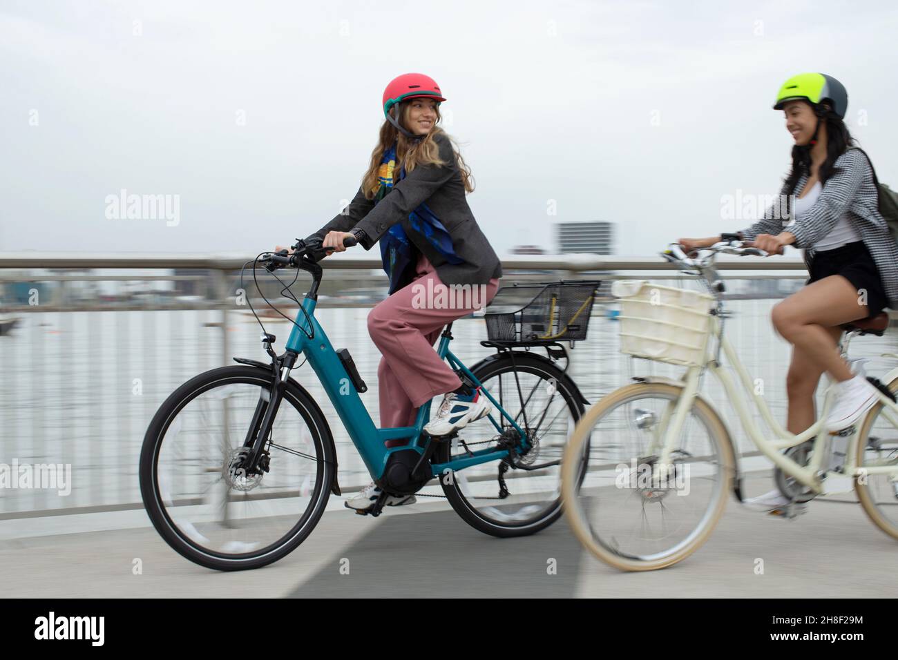 Junge Freundinnen reiten Fahrräder auf der Stadtbrücke Stockfoto