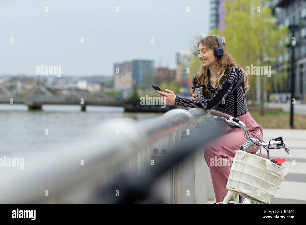 Junge Frau mit Kopfhörern und Smartphone am Stadtstrand Stockfoto