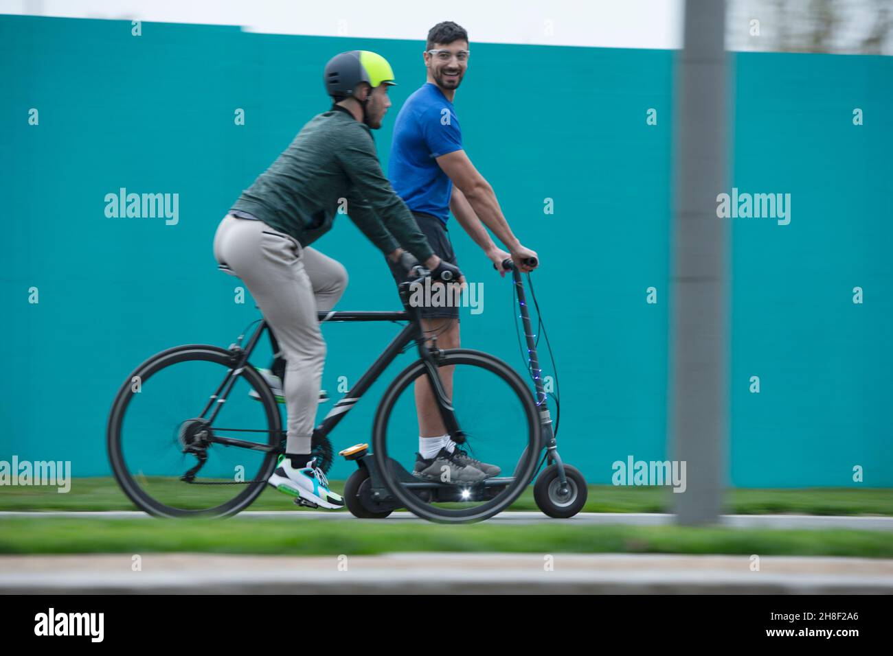 Männer fahren Fahrrad und Roller auf dem Bürgersteig Stockfoto