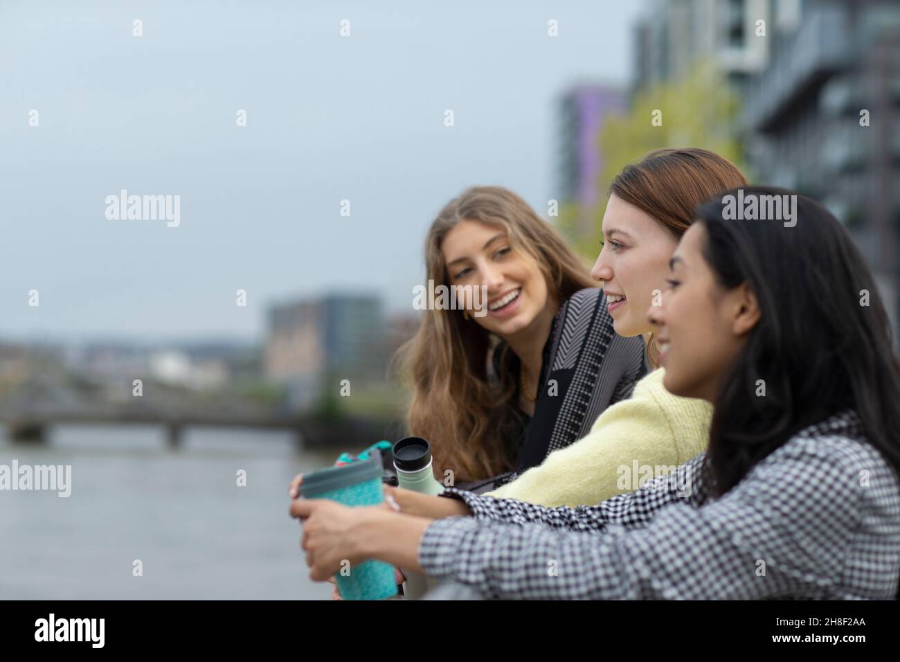 Glückliche junge Freundinnen, die mit Kaffee in der Stadt reden Stockfoto