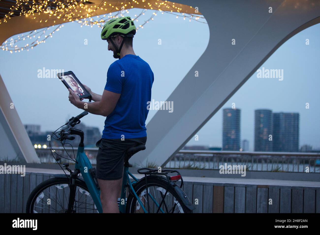 Mann auf dem Fahrrad Video chatten mit digitalen Tablet in der Stadt in der Nacht Stockfoto
