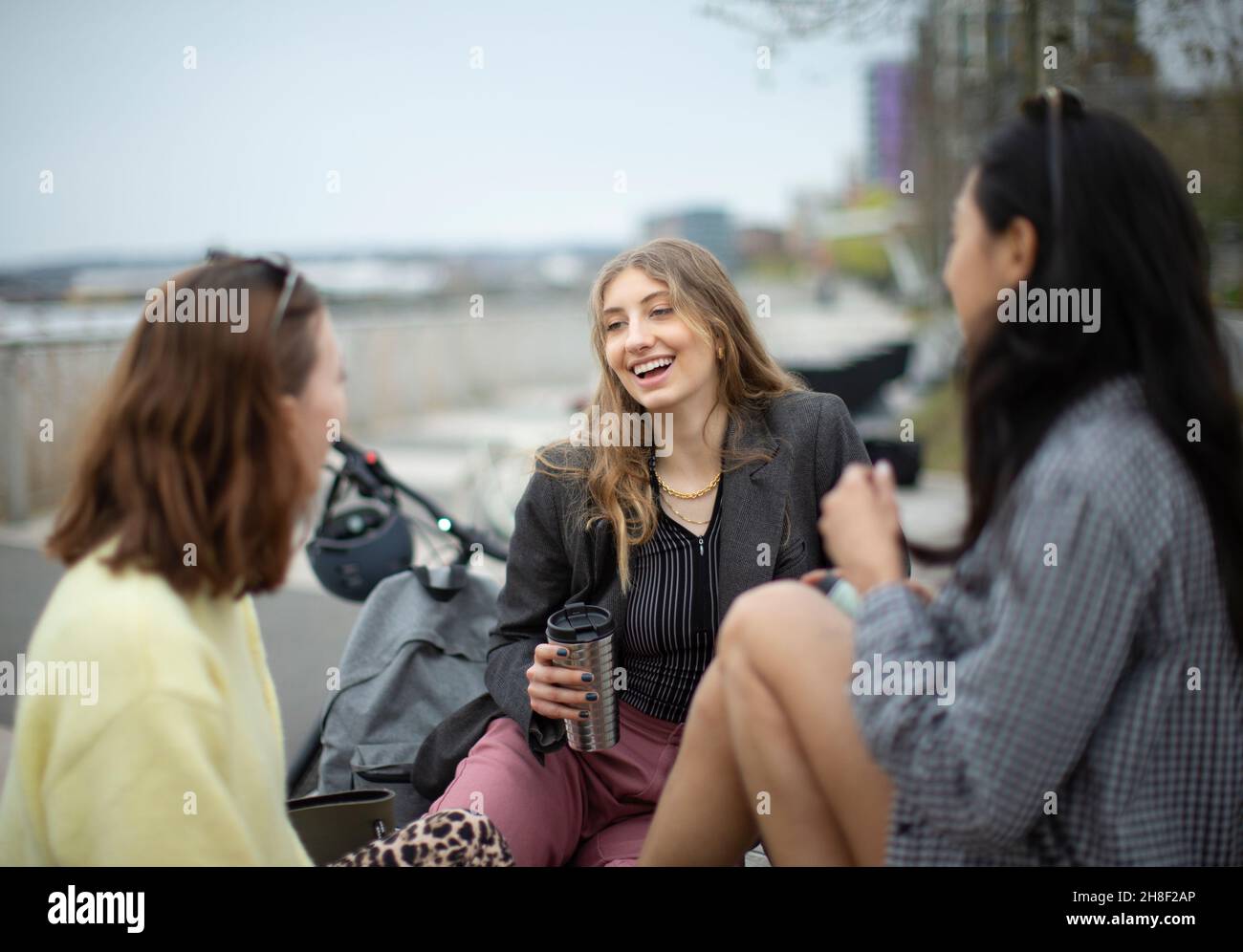 Junge Freundinnen unterhalten sich und trinken Kaffee in der Stadt Stockfoto