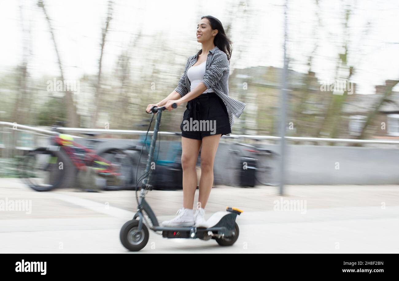 Junge Frau Reiten Elektroroller in der Stadt Stockfoto