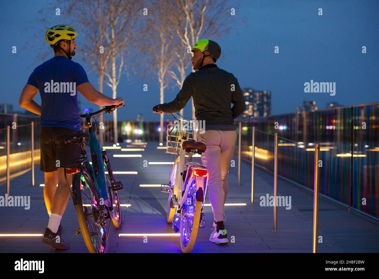 Männer gehen beleuchtete Fahrräder auf einem städtischen Fußweg, London, Großbritannien Stockfoto