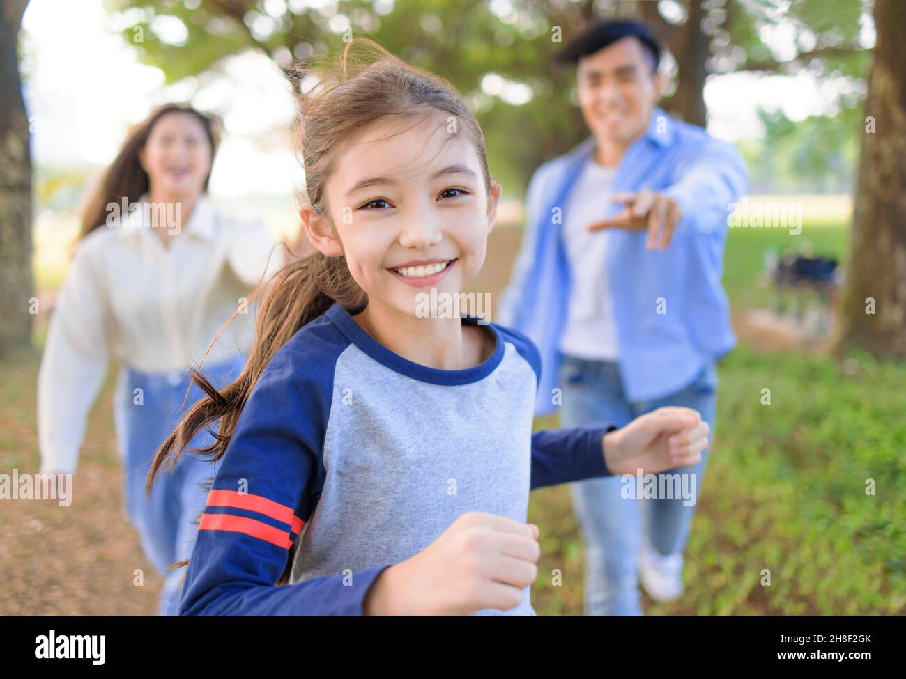 Glückliche Familie mit Tochter läuft und spielt zusammen im Park Stockfoto