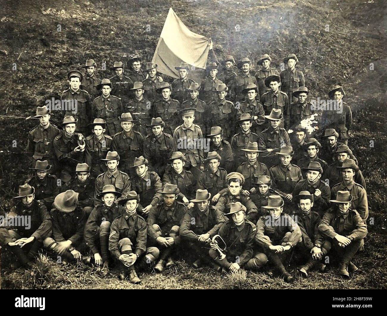 Eine Gruppe australischer Soldaten winkt mit ihrer Bataillonsflagge