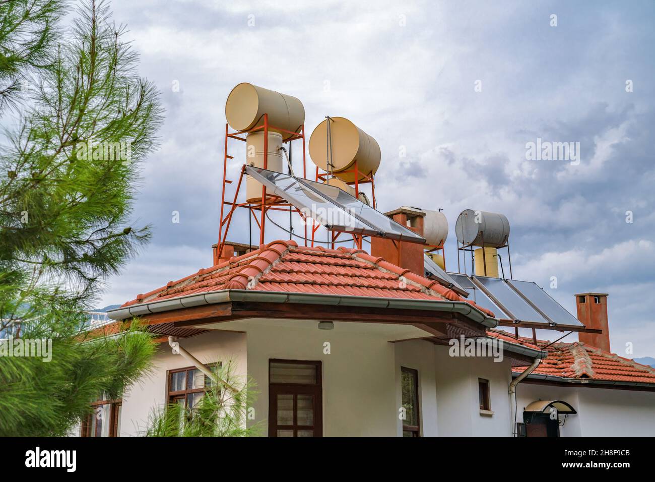 Konzept spart Strom. Wasserfässer, die durch Solarbatterien auf dem Dach des Hauses beheizt werden. Solarenergie. Stockfoto