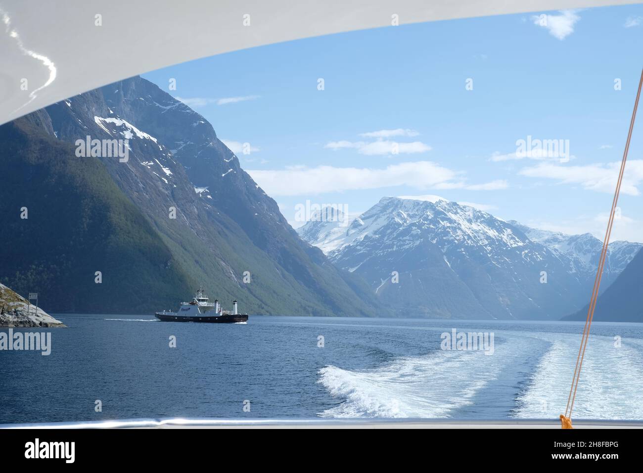 Segeln auf einer Yacht durch die Fjorde Norwegens mit Blick auf ein Boot und die Berge Stockfoto