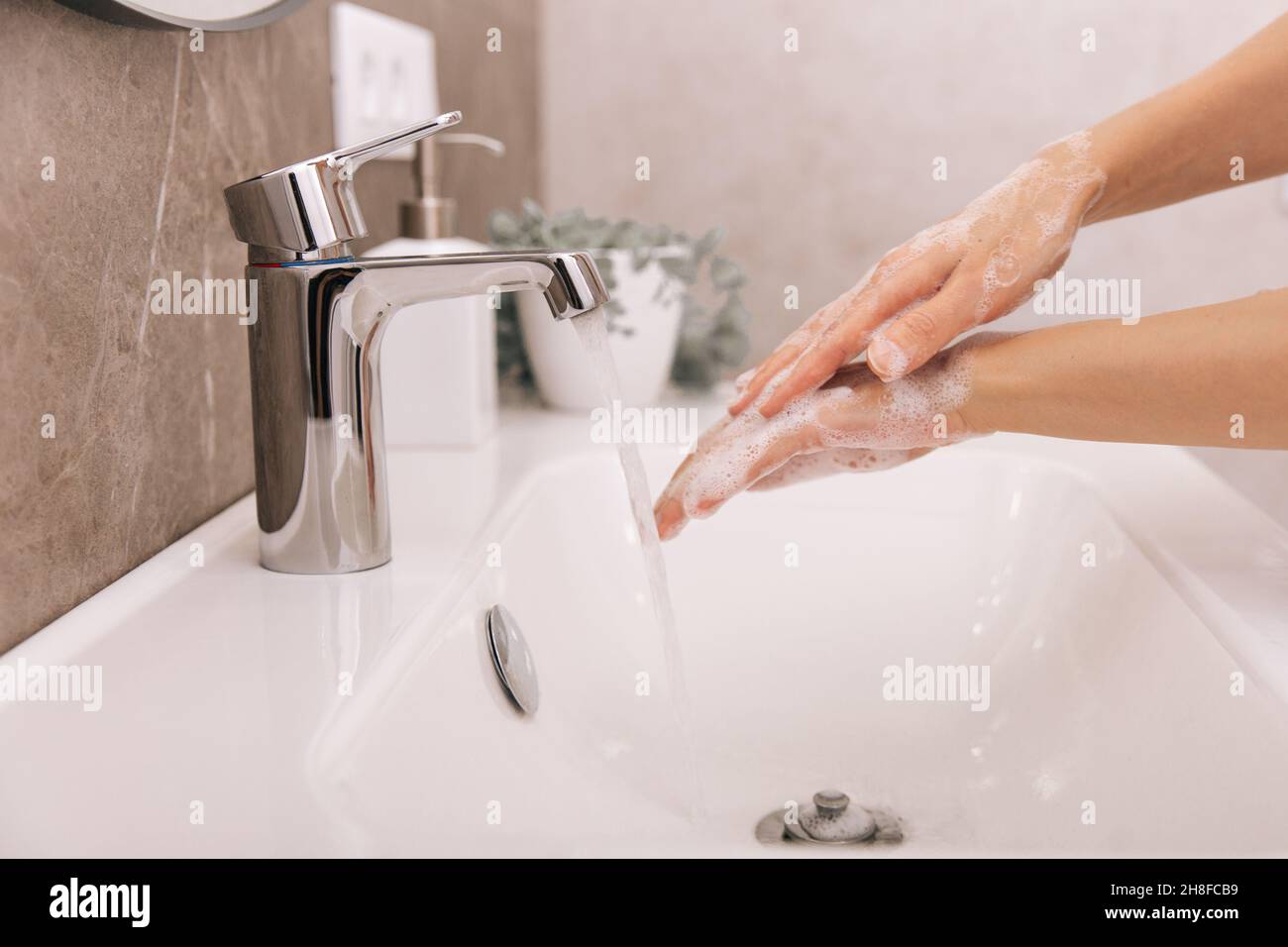 Händewaschen unter dem fliessenden Wasserhahn. Waschen von Händen, reiben mit Seife zur Vorbeugung von Corona-Viren, Hygiene, um die Ausbreitung des Corona-Virus im OP zu stoppen Stockfoto