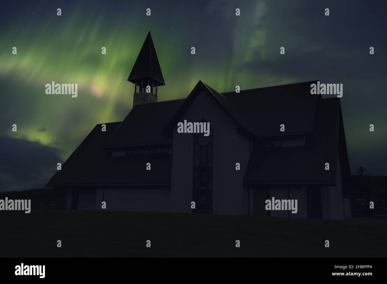 Schöne traditionelle Kirche in der Nähe von Reykjavik Stadt bei einer Nacht mit schönen Nordlichtern. Island Stockfoto