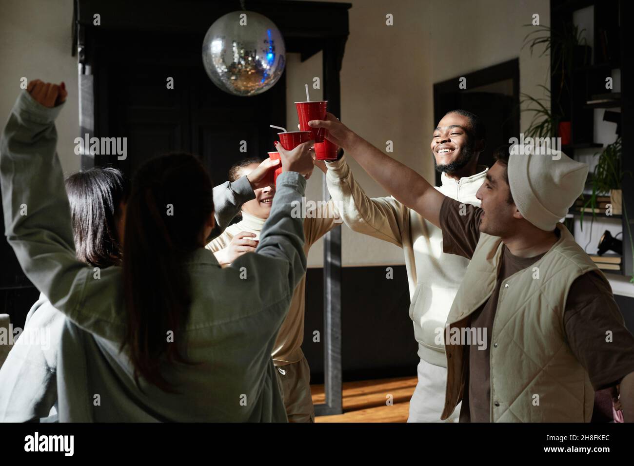 Eine Gruppe von Teenagern toasten mit Plastikbechern, während sie sich auf einer Party amüsieren Stockfoto