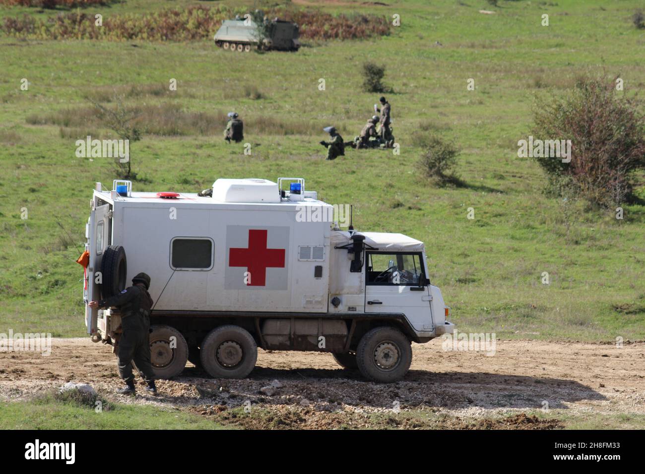 Das rote Kreuz Fahrzeug bei der militärischen Übung mit Menschen in den Bergen Stockfoto