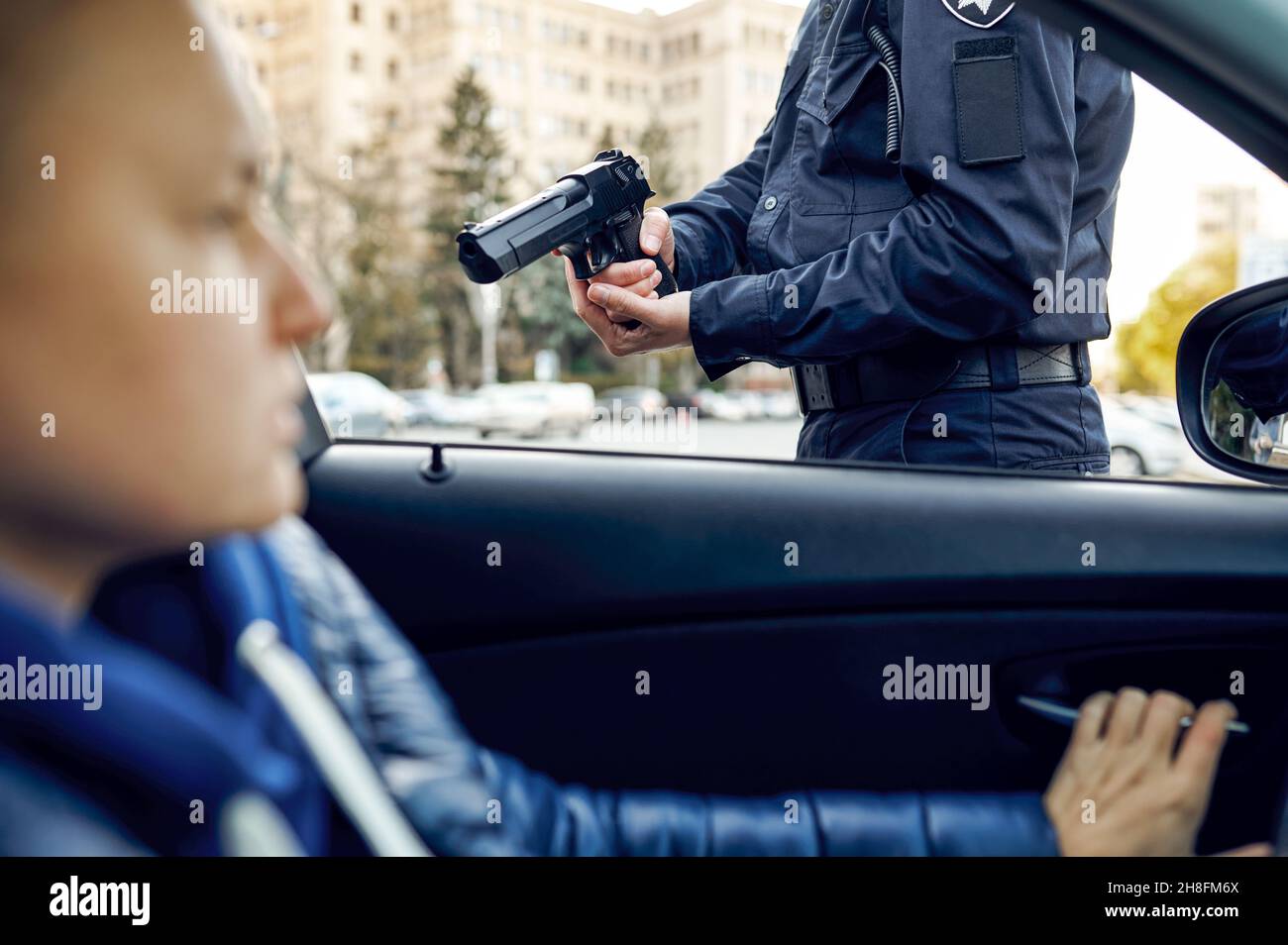 Ein männlicher Polizeibeamter mit Waffe verhaftete eine Fahrerin Stockfoto