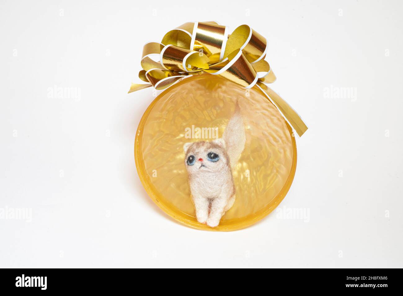 Nadel filzende Katze sitzt in einem goldenen halb Weihnachten Ornament. Katzenanpassung kann schönes Weihnachtswunder sein. Stockfoto