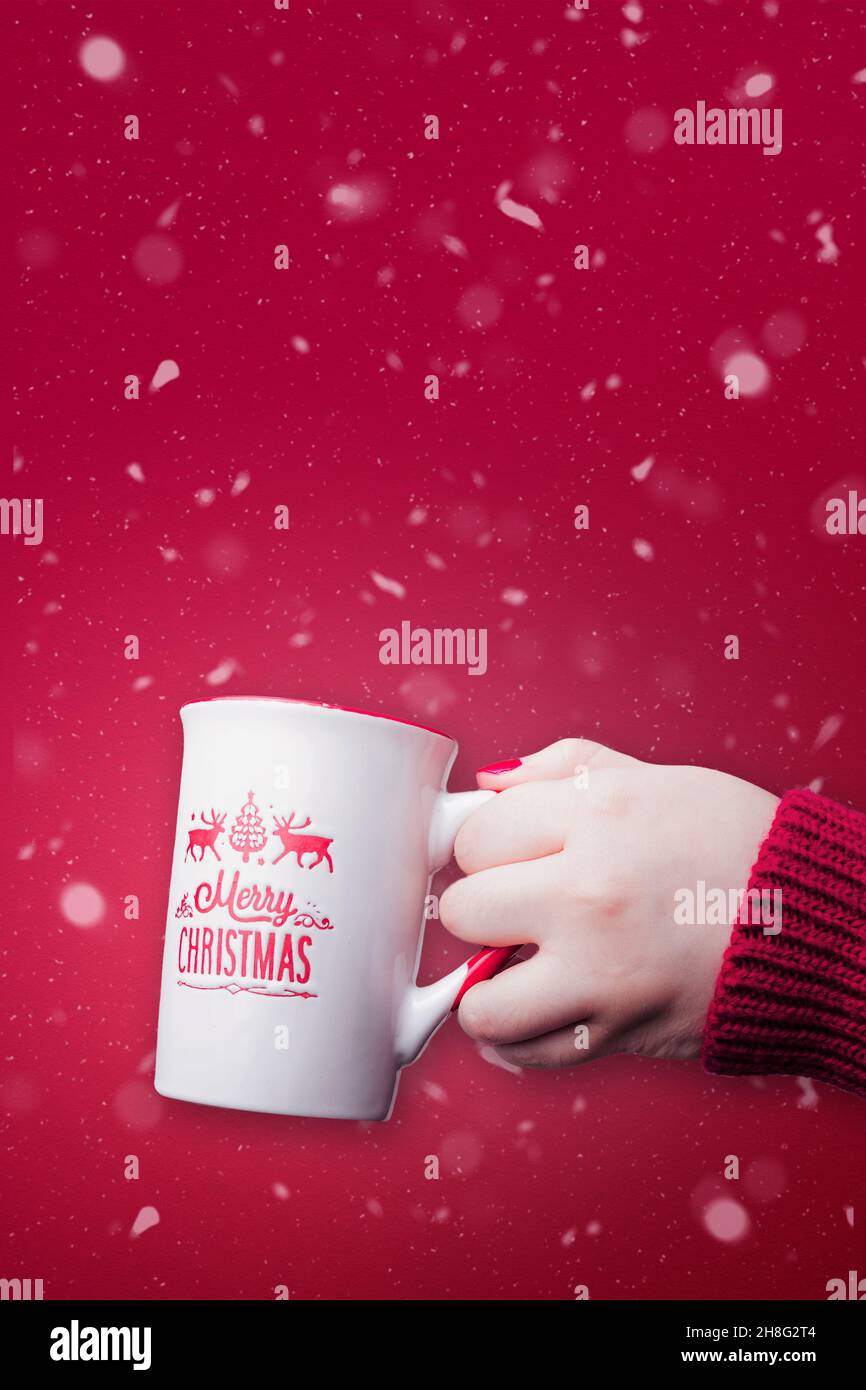 Fröhliche Weihnachtsbecher mit rotem schneebedecktem Hintergrund und Kopierraum. Weihnachtskonzept. Stockfoto