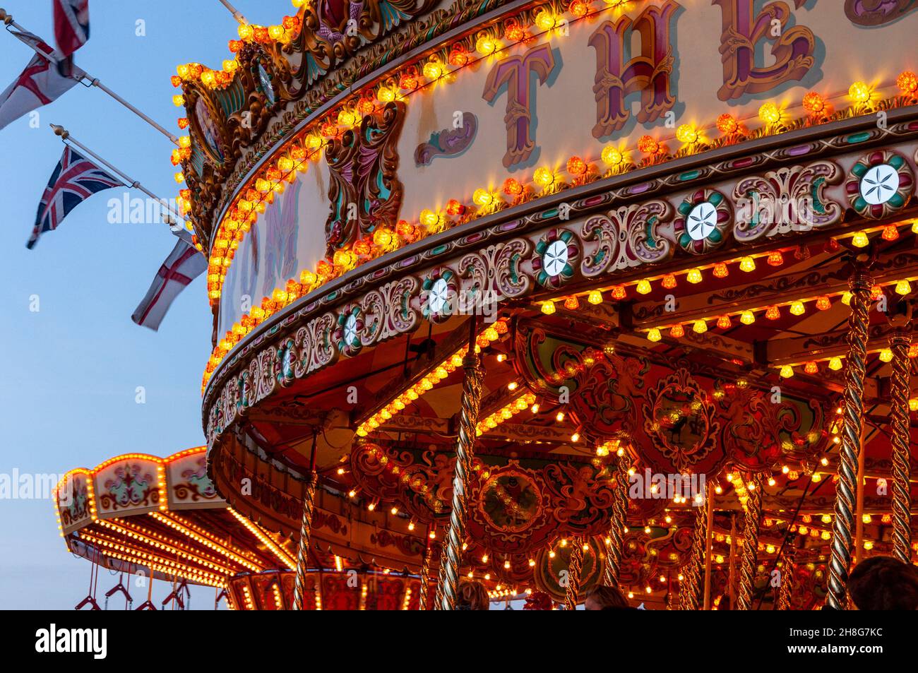 Classic Carousel, Merry Go Round, beim Goodwood Revival Vintage Event 2014, bei Dämmerung mit Lichtern. Vergnügungsfahrt im Kreisverkehr Stockfoto