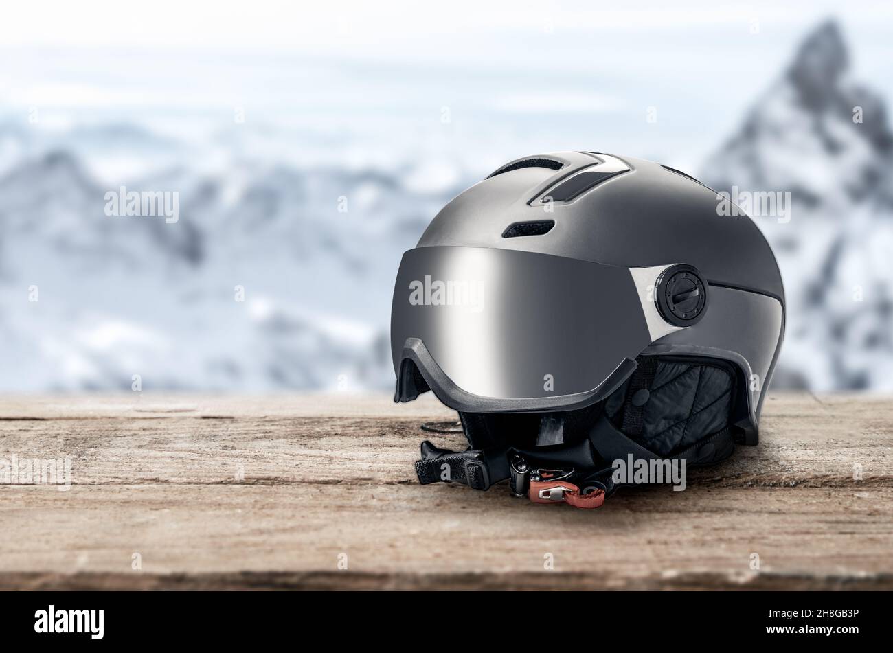 Skihelm mit Visier auf Berge Hintergrund. Moderner grauer Skihelm mit Sonnenblende auf Berge Hintergrund. Wintersport-Helm. Mountain Resort. c Stockfoto